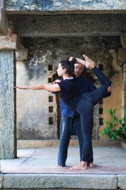 Alan che sostiene l'equilibrio dello studente in Natarajasana (Posizione del Danzatore) durante una sessione di Ashtanga (Serie Avanzata - Sthira Bhaga).
