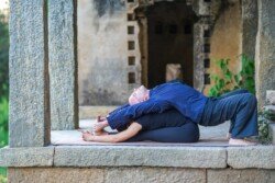 Alan deepening the student's forward bend in Paschimottanasana (Seated Forward Bend) in Ashtanga Yoga (Primary Series - Yoga Chikitsa).