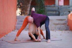 Alan che guida lo studente in Prasarita Padottanasana C (Piegamento in Avanti a Gambe Larghe C) nella sequenza Ashtanga (Prima Serie - Yoga Chikitsa).