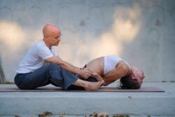 Alan che regola l'arco della schiena dello studente in Supta Vajrasana (Posizione del Fulmine Sdraiato) durante la pratica Ashtanga (Serie Intermedia - Nadi Shodhana).